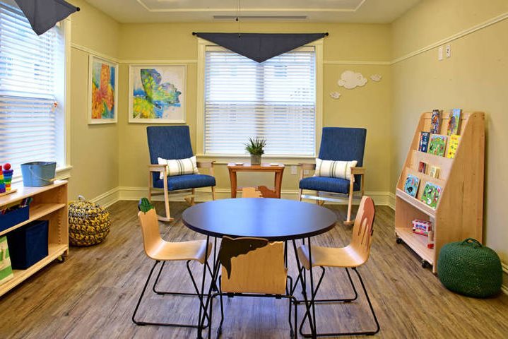 Cozy and inviting childrens reading area with small table, chairs, bookshelves, and colorful artwork