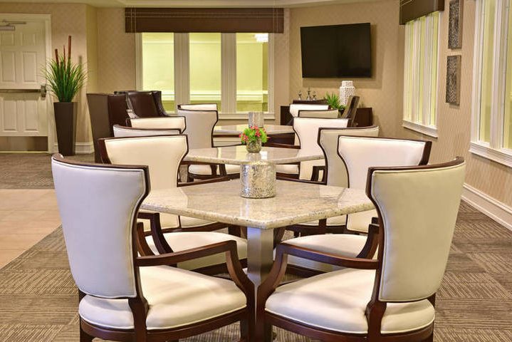 dining area with modern tables, white cushioned chairs, and a mounted TV on the wall