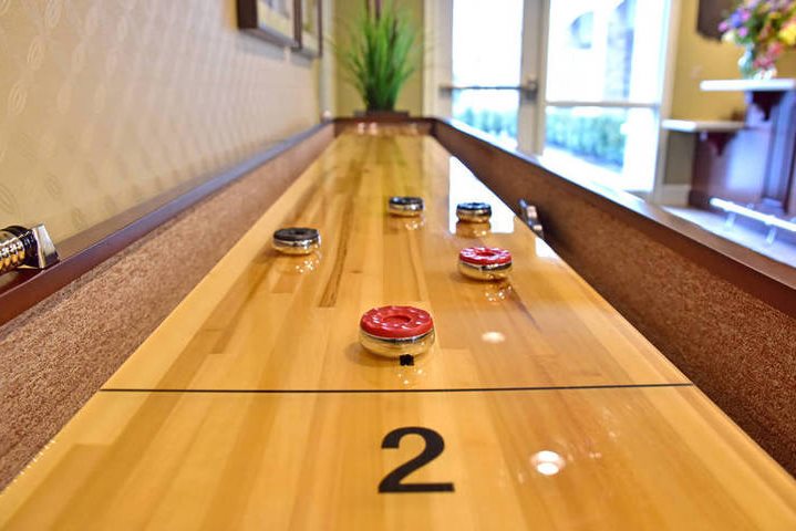 Shuffleboard table with pucks inside a room with natural lighting from a nearby door.