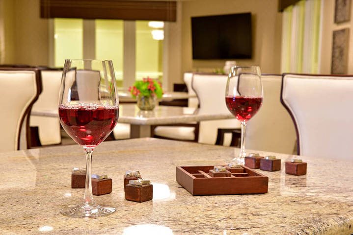 Two glasses of red wine on a granite table along with a wooden game board and dice