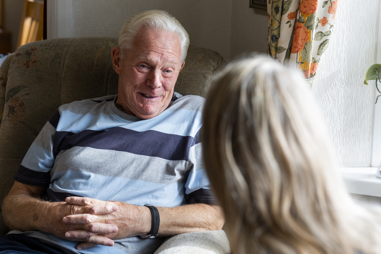 Elderly man smiling while conversing with a woman in a cozy room