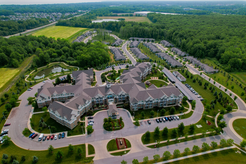 Aerial view of a large residential complex with multiple buildings and roads surrounded by trees.