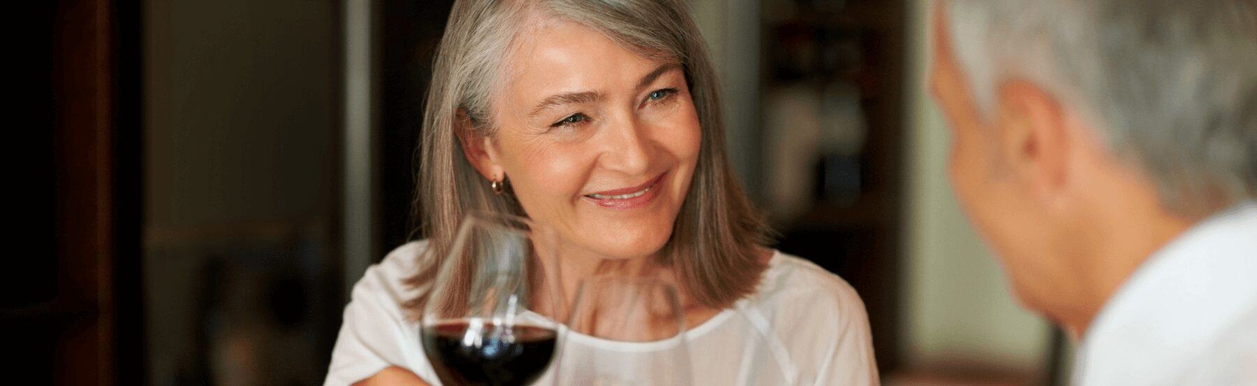 Senior woman clinking wine glass with her husbands